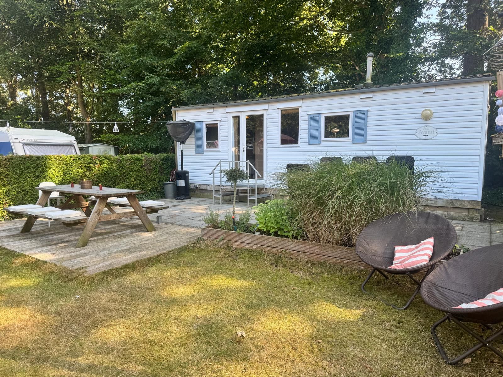 De stacaravan op Buizerd 14 in avondlicht, met tuin, hangstoelen en picknicktafel